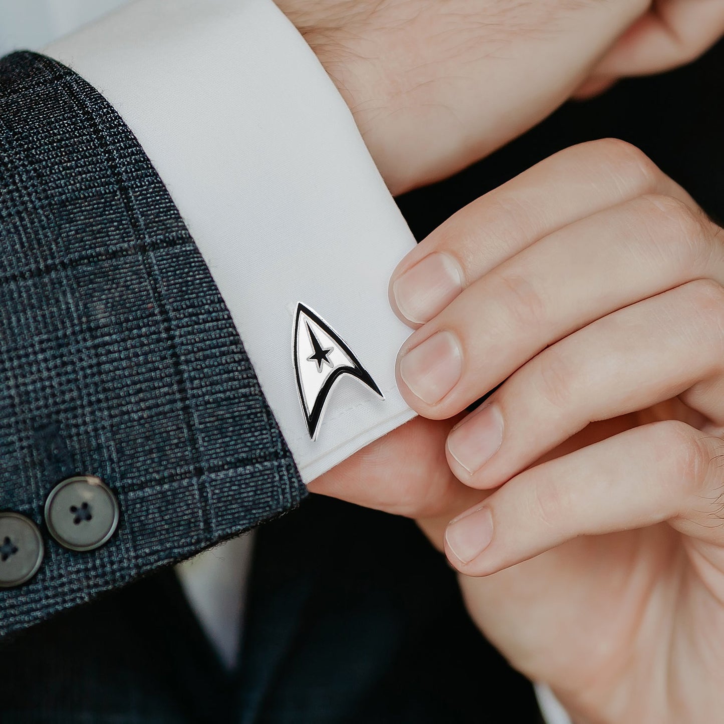 Man wearing Star Trek communicator badge cufflinks on a white dress shirt