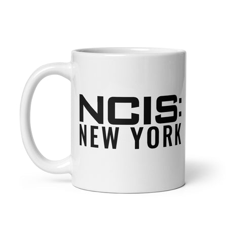 Front angle view of the NCIS New York white ceramic mug showing the brand graphic